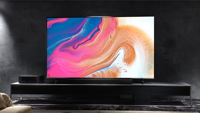 Das Installationsvideo zeigt, wie ein schlanker Fernseher in einem dunklen Raum an der Wand montiert wird.