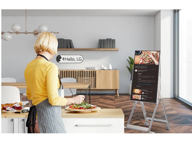 Eine Frau steuert den One:Quick Flex beim Kochen per Sprachbefehl.