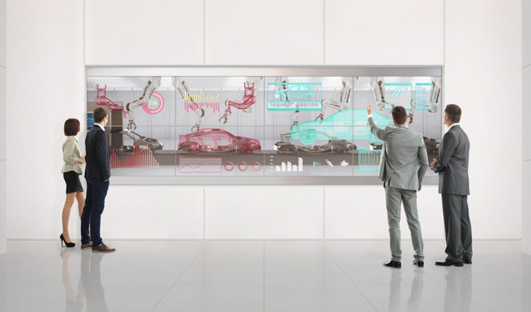 Personen analysieren ihre Arbeit auf den transparenten OLED-Bildschirmen, die an der Wand der Lobby installiert sind.