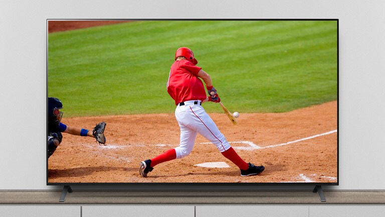 Der Fernseher steht auf dem Standfuß, und auf dem Bildschirm ist ein Baseballspiel zu sehen.