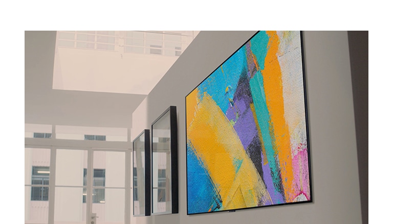 Eine Frau und ein Mann bringen einen Fernseher an der Wand an – Schritt für Schritt und unter Zuhilfenahme einer Wandhalterung und eines Zubehörsatzes, der eine Papierschablone und eine Pappschachtel umfasst, welche die Installation erleichtern. (Video abspielen)