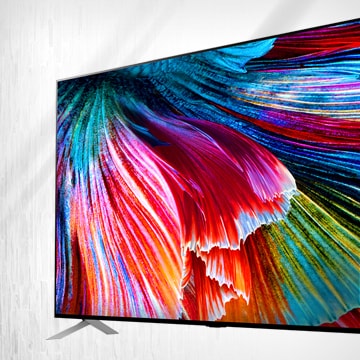 Der LG QNED MiniLED TV steht vor einem hellen Hintergrund, und der Bildschirm zeigt eine Nahaufnahme von leuchtend bunten Blütenblättern.