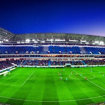 Ein weiter Blick auf ein Fußballstadion mit Menschenmenge und einem gerade laufenden Spiel.