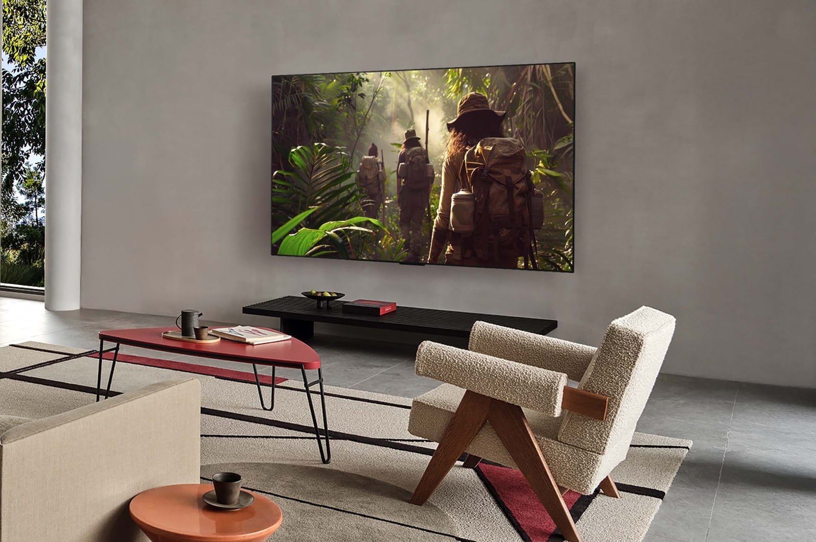 Weite Ansicht eines Wohnzimmers in einem hochwertigen Haus. Ein Mann sieht sich einen Film auf seinem an der Wand montierten LG OLED-Fernseher an. Das Design des Fernsehers fügt sich elegant in die Wand und die Inneneinrichtung ein.