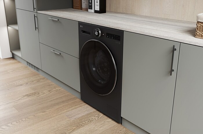 Die LG 9 kg Waschmaschine F4WX9092B in Matte Black, installiert in einer modernen Küche, um ihr schlankes, integriertes Design zu zeigen, mit Energieeffizienzklasse A-55%.