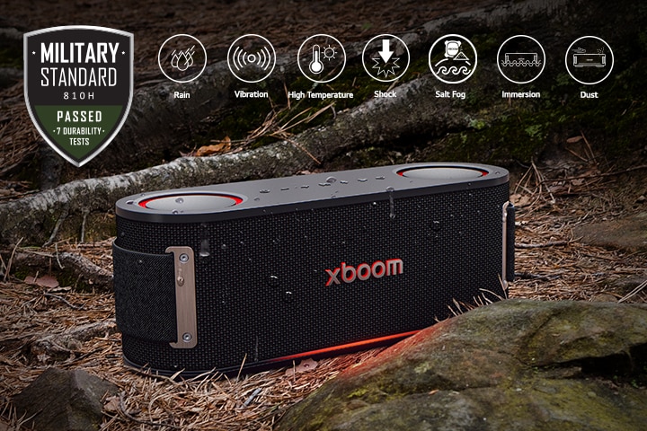 xboom Bounce is placed on soil covered with wet leaves, between a tree root and a stone. On the above left side Military standard logo is placed.	