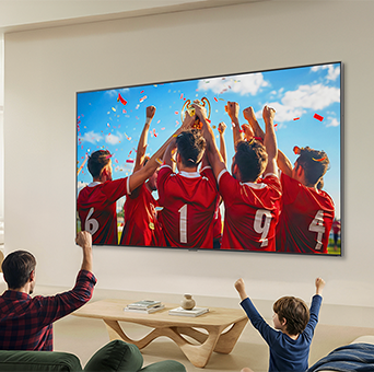 LG QNED evo AI QNED85 Mini LED Ultra Big TV is wall-mounted in a living room, displaying a sports victory celebration with vivid colors and refined picture quality across the wide screen as a family seated on sofas cheers together.