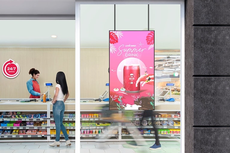 A large LED display is installed on the window inside the convenience store, vividly and brightly showcasing advertisements through the glass.