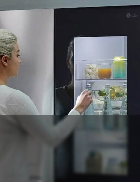 Image shows women adding large round ice balls to a glass in a kitchen