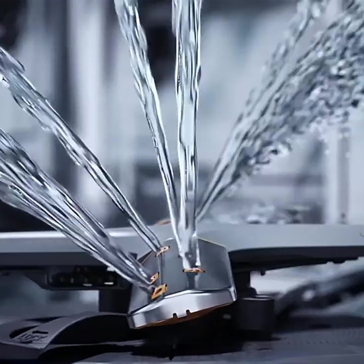 Footage of intense water streaming at different angles from rotating dishwasher blades in close-up.