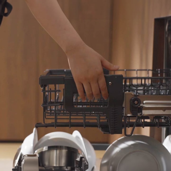 Video of a person raising a dishwashing rack to allow more height space for the lower rack and then placing a frying pan on the lower rack.