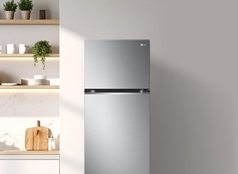 There is a tall LG top mount refrigerator on the side of a minimal wall.