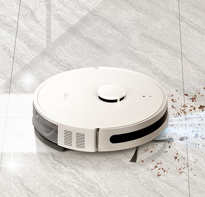 Robot vacuum simultaneously suctioning and mopping a marble floor, with dust in front and a shining floor behind. 