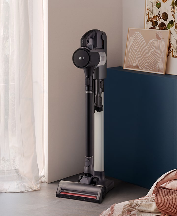 A9L vacuum standing in a bright, stylish living space near a cabinet and sofa.