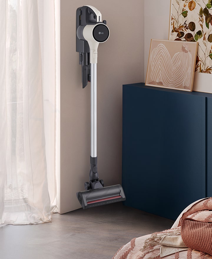 A9L vacuum standing in a bright, stylish living space near a cabinet and sofa.