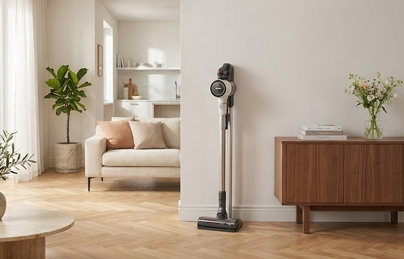 LG all-in-one tower vacuum cleaner standing on a wood floor in a bright living room beside a walnut console.