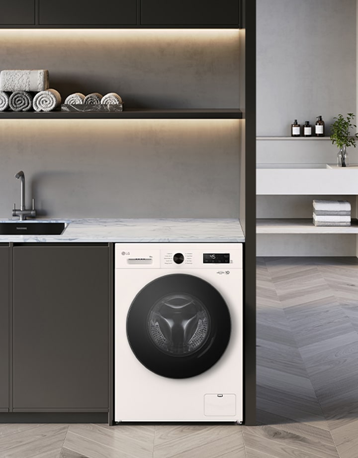 Image shows stylish exterior of a white washing machine with a black glass door in a laundry setting.