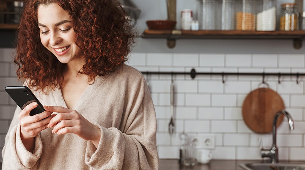 This is an image of a woman looking at a food recipe on her smartphone.