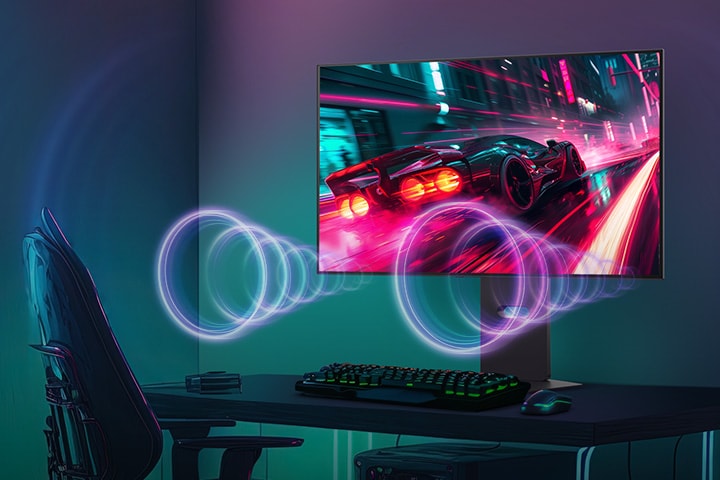 The monitor screen shows a racing game, while sound is coming from the speakers at the bottom of the monitor.