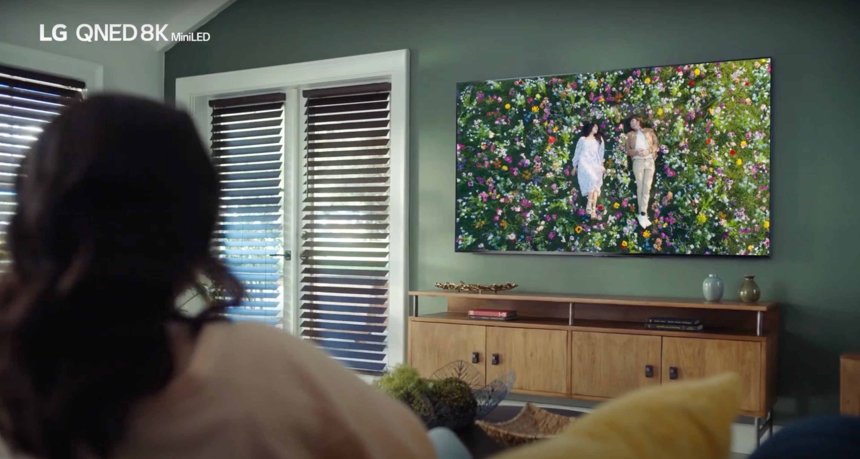 Modern living room with a wall-mounted flat-screen TV. There is a wooden cabinet under the mounted TV.