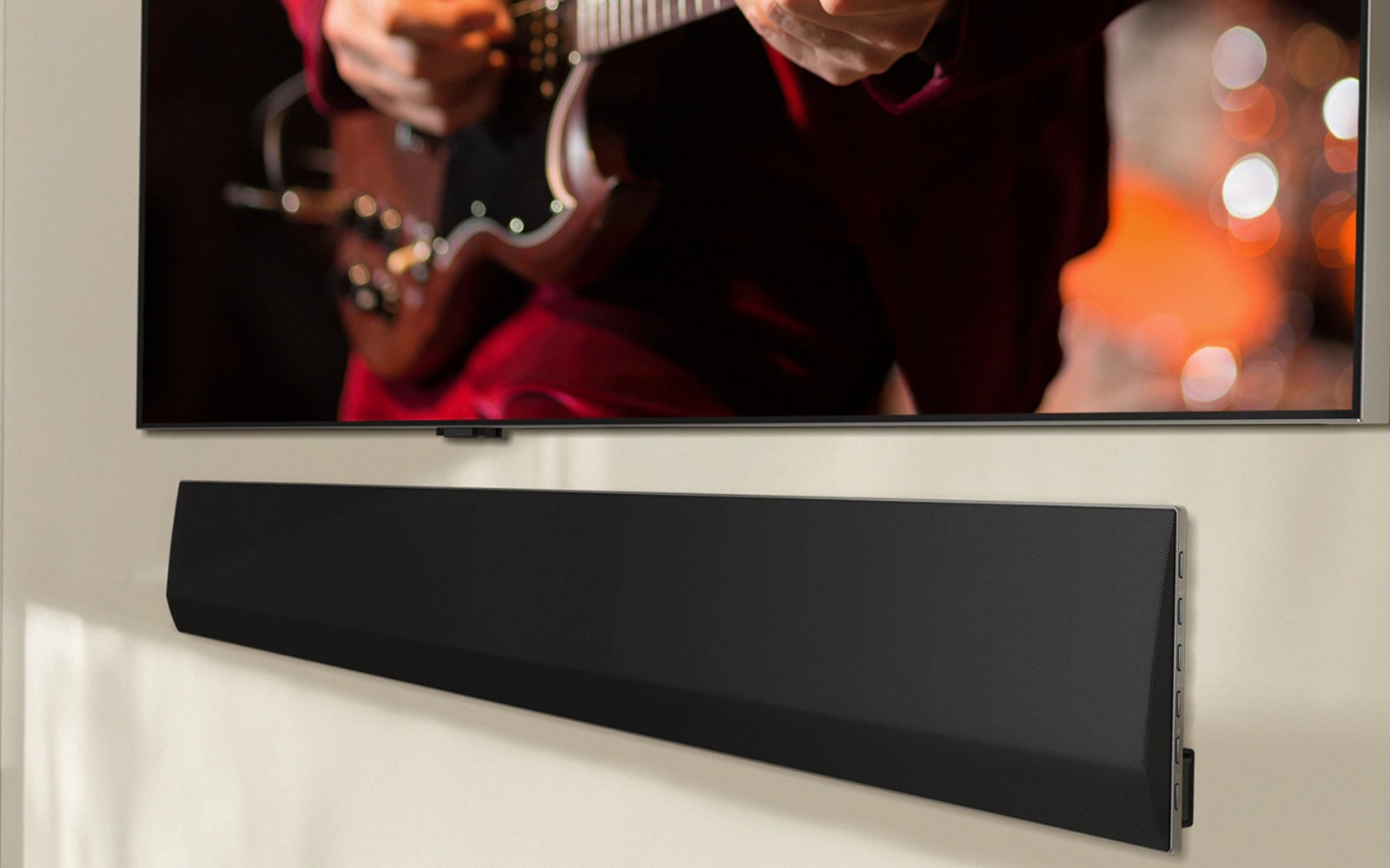 LG soundbar below a TV screen displaying a person playing an electric guitar. The focus is on their hands and the guitar, with a warm, blurred background, creating a cozy atmosphere. The setup highlights a high-quality entertainment system.