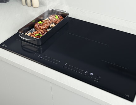 The food on the pan on the induction cooktop is steaming.
