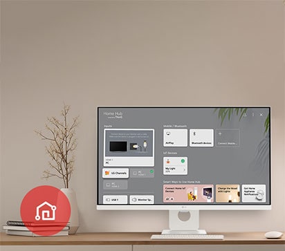 On the table, the monitor displays the Home dashboard screen, with the LG ThinQ App icon visible in the bottom left corner.