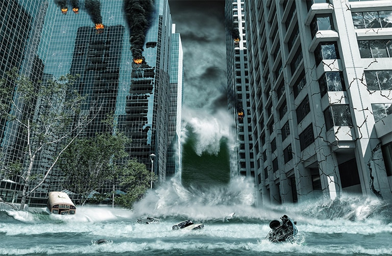 A flooded street with people and vehicles floating in the water and buildings crumbling to either side.