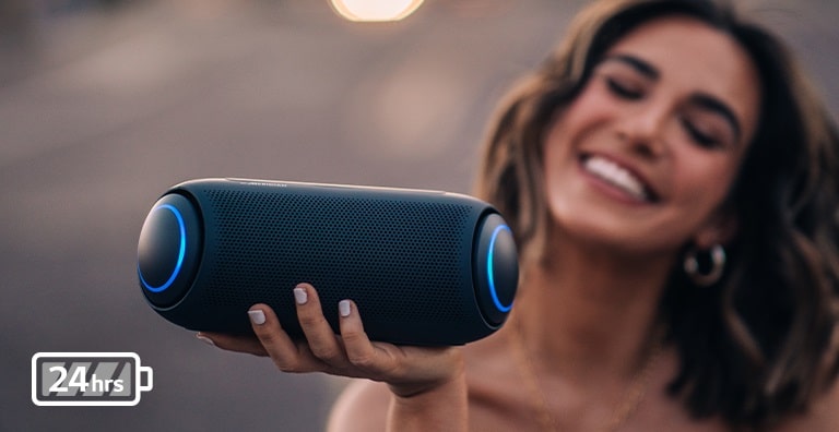 LG XBOOM Go tilts to the left and floats in the air. The woofer lighting is magenta.
