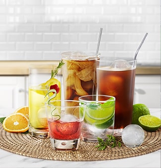  A person is holding a cup containing a drink in one hand and scooping craft ice in the other hand.