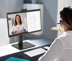 A woman wearing a headset is video conferencing with the built-in webcam.	
