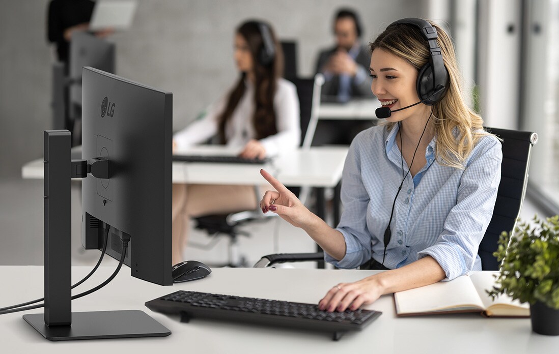 A woman wearing a headset is working while staring at a monitor.