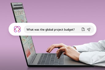 This image shows hands typing on a laptop with a search bar displaying the question, 'What was the global project budget?'