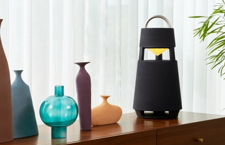 Woman sits indoors relaxing with LG Speaker