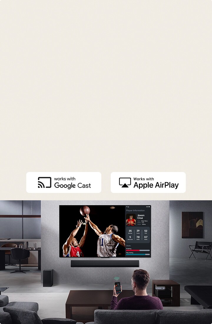 Een persoon in een woonkamer die een telefoon vasthoudt. Op de telefoon staat een zendpictogram dat aangeeft dat het telefoonscherm wordt gespiegeld op de TV. Op de tv is een basketbalwedstrijd te zien en aan de zijkant staat een gespiegeld scherm met spelersstatistieken.