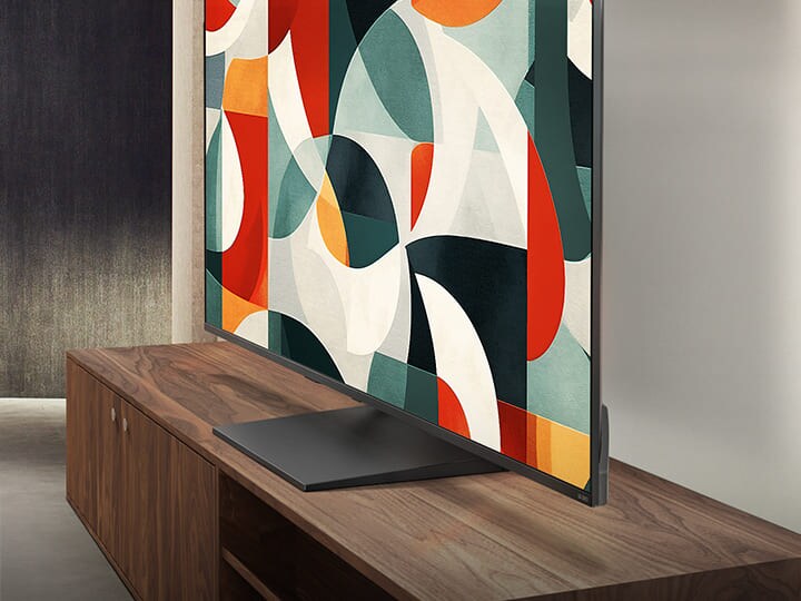 LG QNED TV boven een tv-lade in een moderne woonruimte. LG QNED TV toont een abstracte achtergrond in groen, rood en oranje.