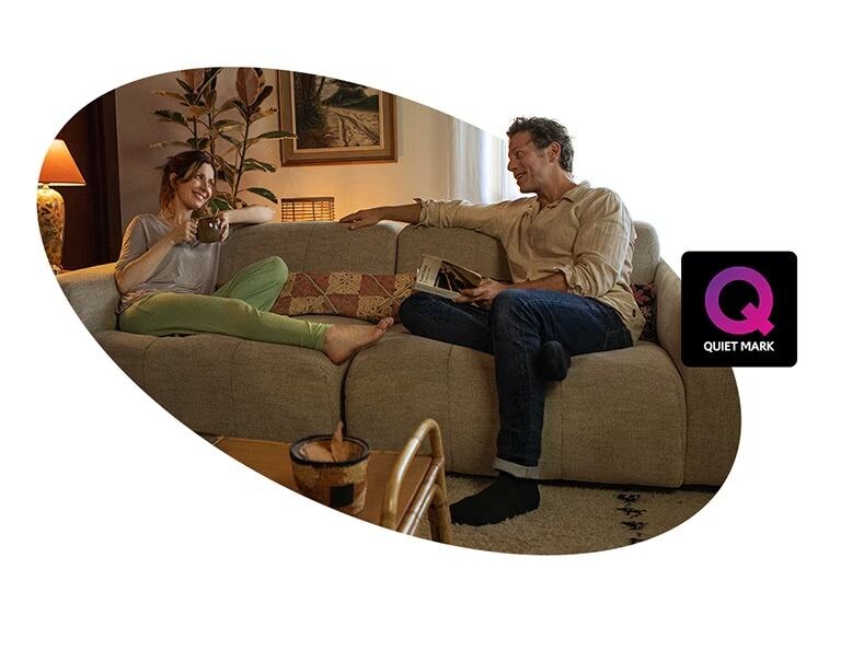 Een volwassen vrouw en een man zitten op een bank in huis en praten met een glimlach. Er staat een Stilte Markering-certificeringslogo naast de afbeelding.