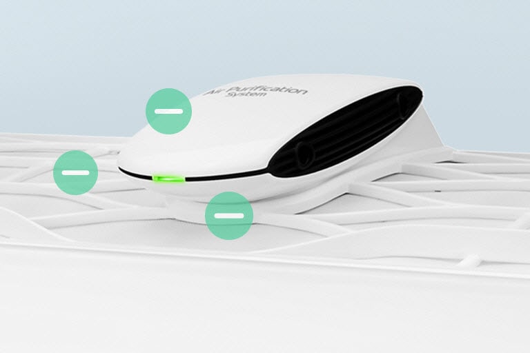 Een zijaanzicht van de Ionenverspreider op de machine met een groen licht aan de voorzijde. Er zijn drie groene cirkels met negatieve ionensymbolen in het midden bij de diffuser.