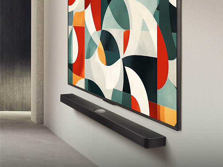 Een schuin aanzicht van een LG QNED TV aan de muur boven een LG Soundbar in een moderne woonruimte. LG QNED TV toont een abstracte achtergrond in groen, wit, rood en oranje.	