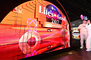 Bezoekers bekijken het gebogen LED-display van LG met de slogan 'Life's Good 24/7' tijdens een technologiebeurs.
