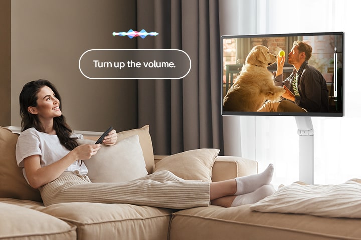 Een vrouw zet het volume van de LG Smart Monitor Swing hoger met een Magic Remote.
