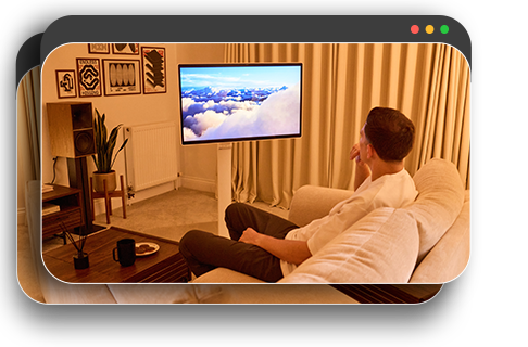 Een man die ontspant in een schemerige kamer en een film kijkt op een monitor.