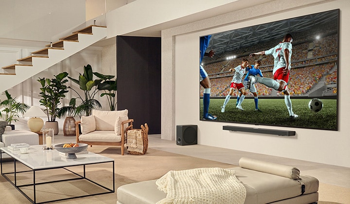 Een gezin zit gezellig bij elkaar voor hun LG ultragrote tv en kijkt naar een spannende voetbalwedstrijd op het enorme scherm.