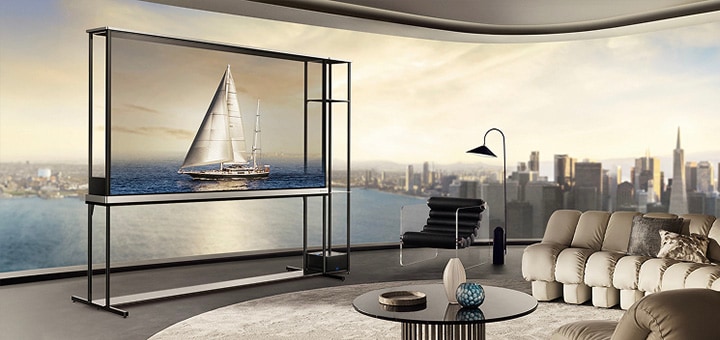 Een LG OLED T4 in een penthouse. De ramen geven uitzicht op de skyline van de stad en de oceaan. De LG OLED T4 staat in de transparante modus en toont een afbeelding van een jacht. Door de positie van de tv en de transparantie van het scherm lijkt het alsof het jacht buiten op de oceaan drijft.
