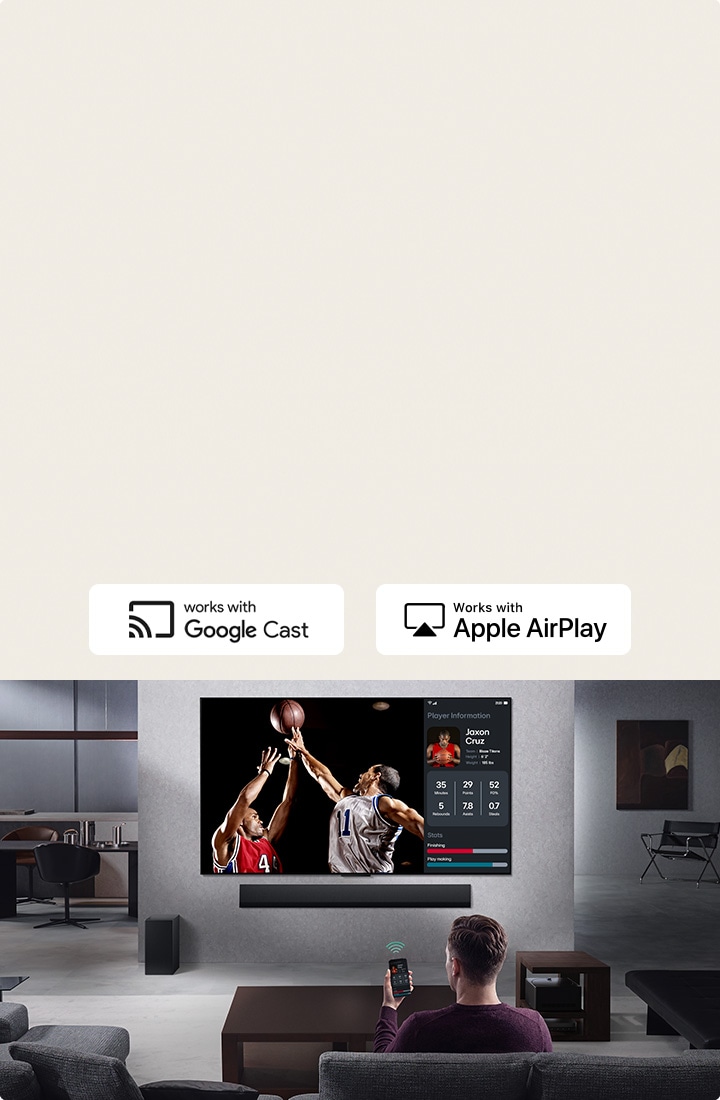 Een persoon in een woonkamer die een telefoon vasthoudt. Op de telefoon staat een zendpictogram dat aangeeft dat het telefoonscherm wordt gespiegeld op de TV. Op de tv is een basketbalwedstrijd met spelersstatistieken.