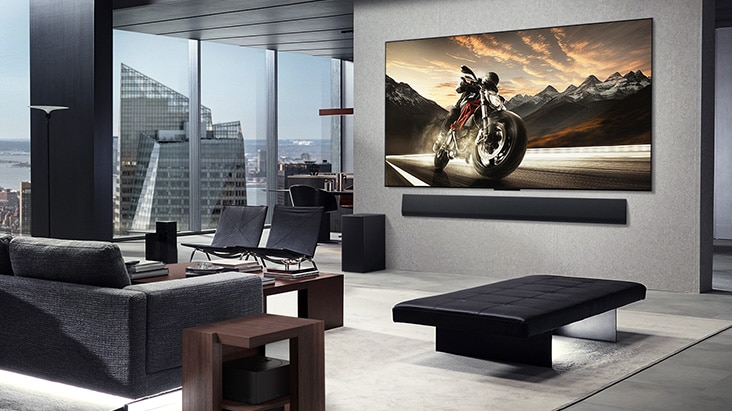 Een aan de wand gemonteerde LG OLED M5 TV en LG Soundbar in de woonkamer van een chic appartement. De Zero Connect Box is verborgen onder een bijzettafeltje.