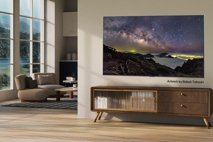 Interieur van een landelijk huis. Een enorme aan de muur gemonteerde LG TV toont een prachtig natuurlijk landschapskunstwerk op het scherm. De TV lijkt op een foto die aan de muur hangt.