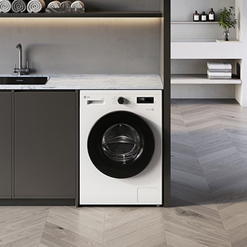 De LG 9 kg wasmachine W4X1085NWB in Essence White, ingebouwd onder het aanrecht in een moderne wasruimte.
