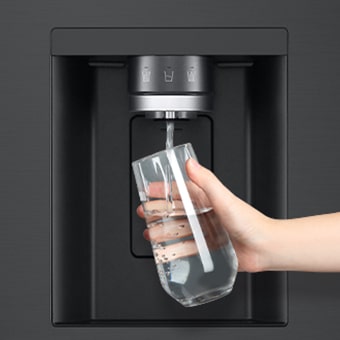 Une personne prend de l’eau du distributeur du réfrigérateur dans un verre