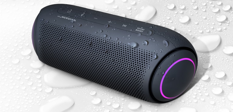 Op een witte achtergrond is de LG XBOOM Go naar links gericht. Er zitten waterdruppels op en onder de LG XBOOM Go.